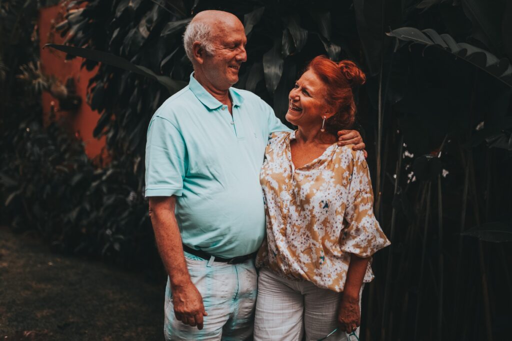 An elderly couple standing and looking at each other happily